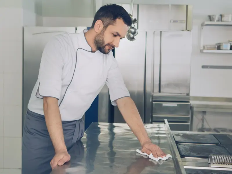 Keukenmedewerker reinigt een werkblad