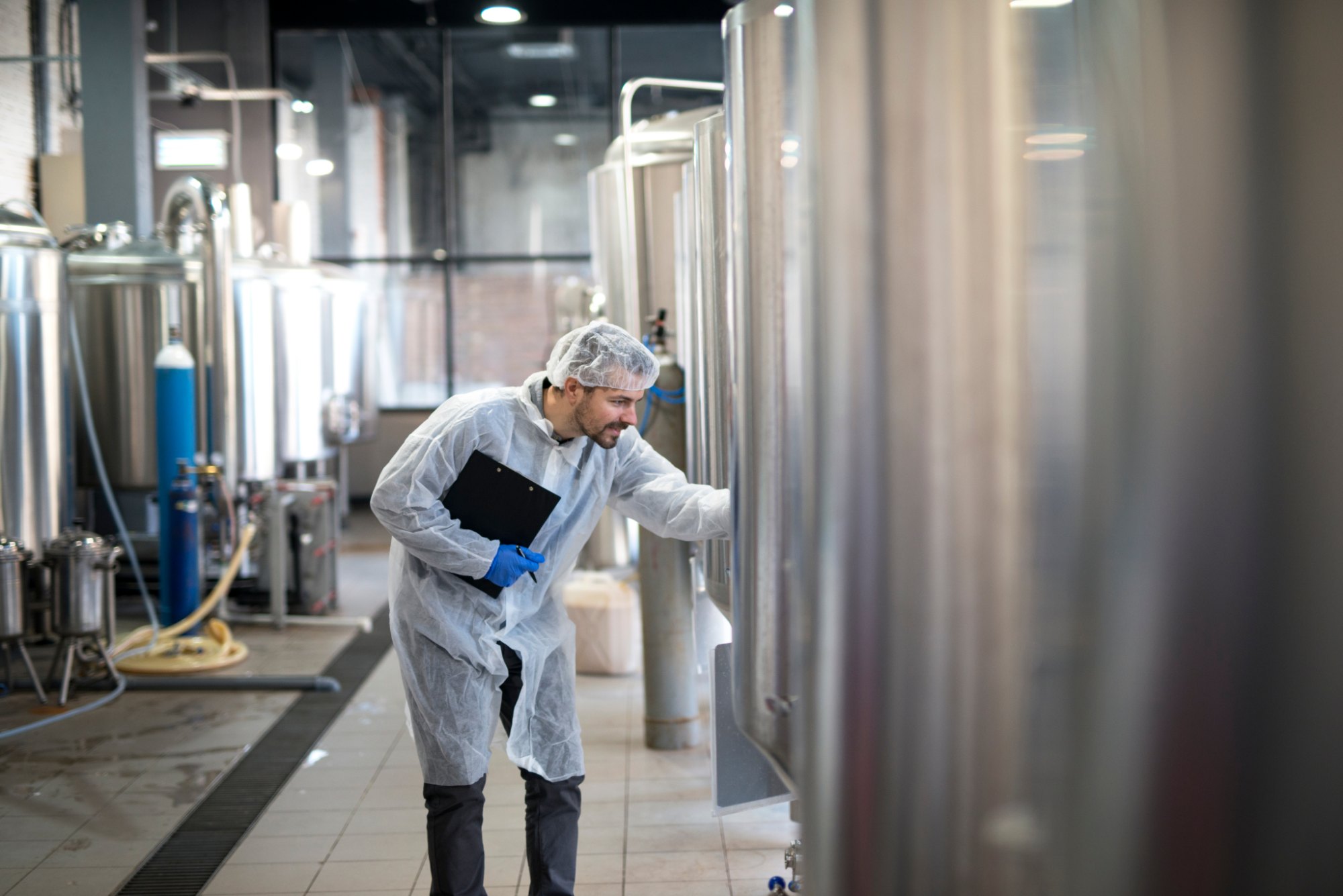 Medewerker inspecteert tanks in een voedingsfabriek