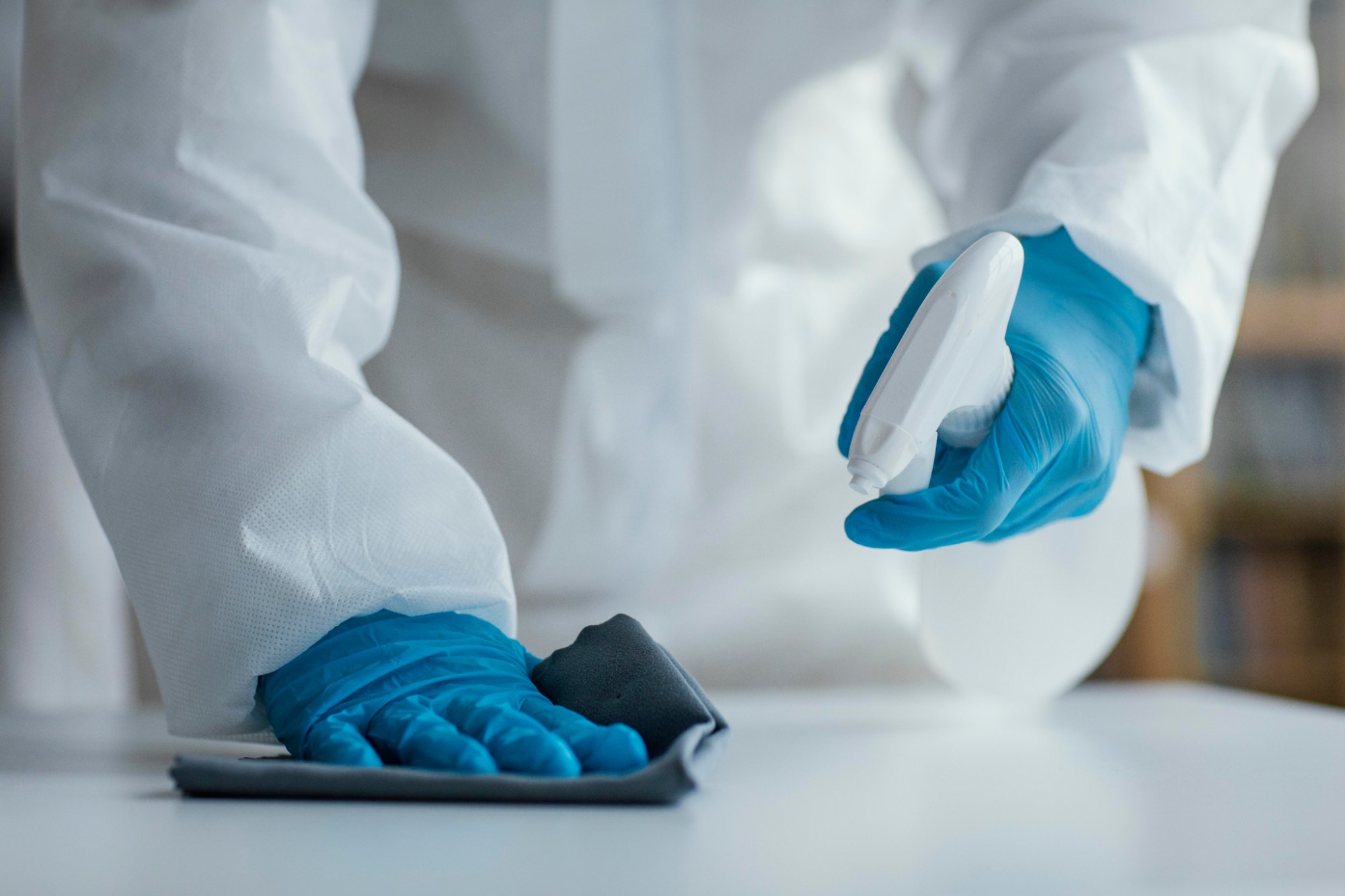 Handen met blauwe handschoenen reinigen een oppervlak
